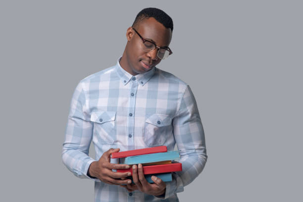 istock A dark-skinned man in a plaid shirt holding books 1330240321