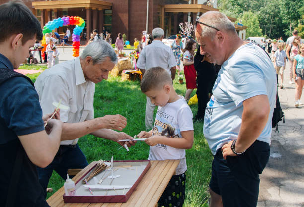 Man volunteer teaching boys to make toy cardboard planes stock photo