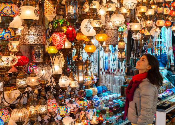 joven sonriente mirando lámparas turcas en venta en el gran bazar, estambul, turquía - bazaar fotografías e imágenes de stock