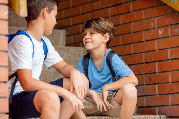 istock Smiling boys sitting at the stairs and talking. 1330242504