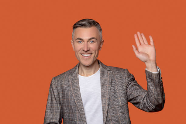 istock Smiling man with raised hand in greeting 1330244800