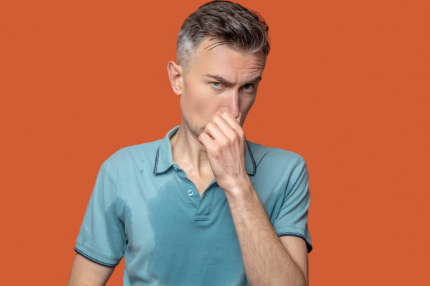 istock Man in tshirt with wet spots touching nose 1330244847