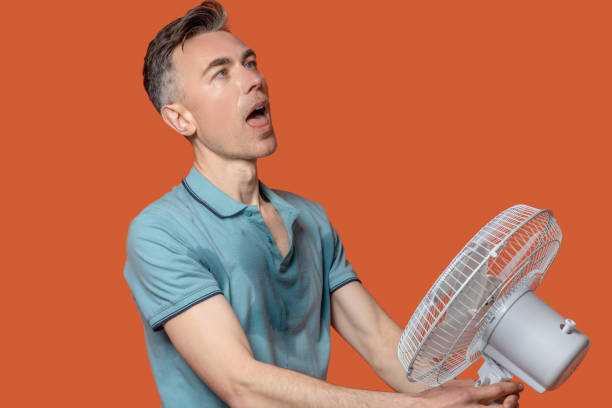 istock Man with open mouth near running fan 1330244996