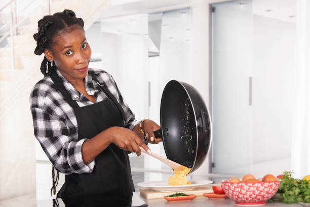 istock Smiling afro american woman moving scrambled eggs into a plate 1330247607