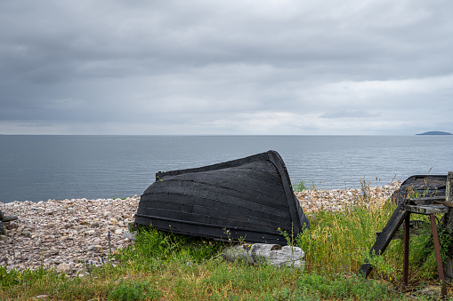 An old wooden boat on the seashore. Picture from the Baltic Sea. Blue sky and ocean in the background.