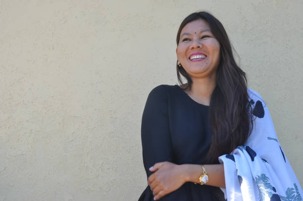 una hermosa joven nepalí sonriendo con kurta negra, de pie contra la pared amarilla con mirar de reojo, copiar el espacio - 1818 fotografías e imágenes de stock