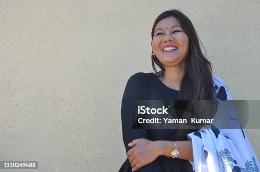 istock A beautiful Nepali young girl smiling with wearing black kurta, standing against yellow wall with looking sideways, copy space 1330249488