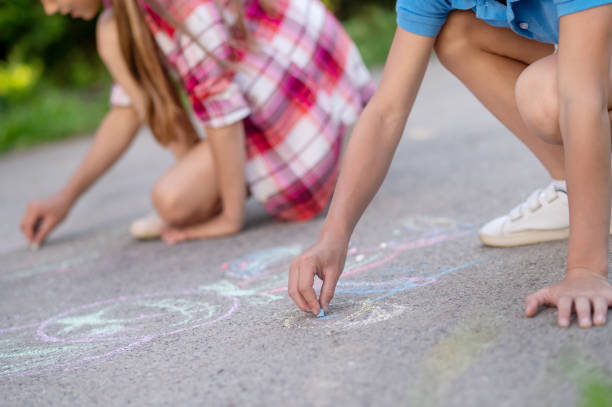 istock Childrens hands drawing with crayons on asphalt 1330261316