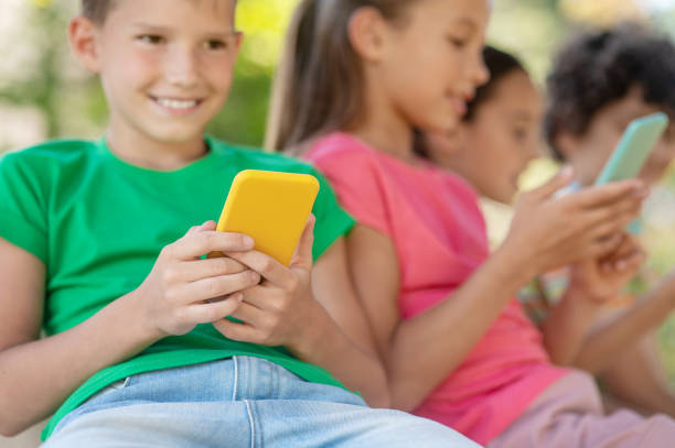 istock Joyful boy with yellow smartphone and friends 1330261376