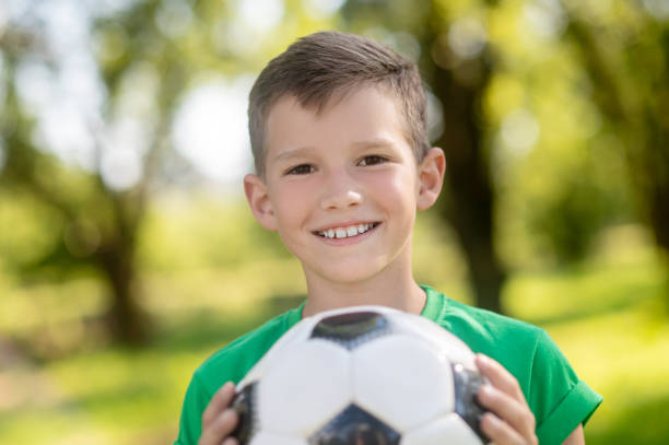 istock Smiling friendly boy with ball in hands 1330261412