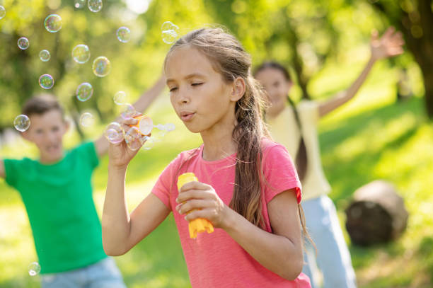 istock Girl blowing air and flying soap bubbles 1330261429