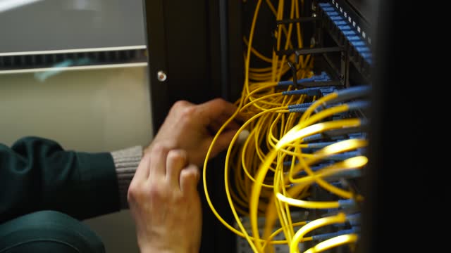 Worker connects optical line internet wire in connection box. Service man soldering optical fiber. Internet service provider engineer working in server room with the optic fiber and router wiring