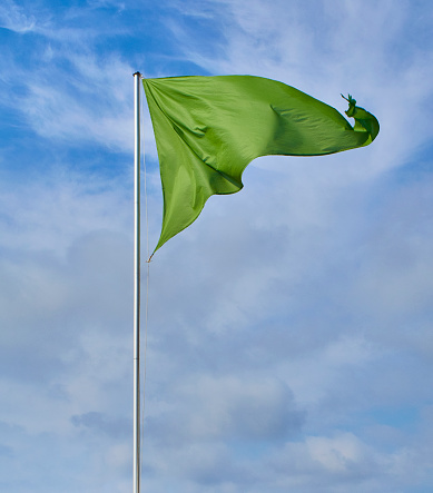 A triangular green flag over a cloudy sky.