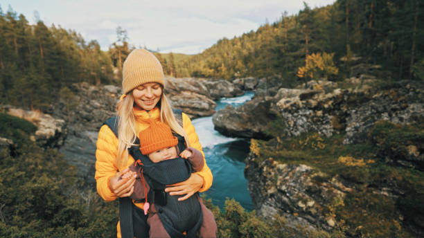 mère marchant avec un porte-bébé dans la forêt famille voyageant en norvège vacances en plein air femme avec enfant en bas âge ensemble mode de vie sain saison d’automne - baby carrier photos photos et images de collection