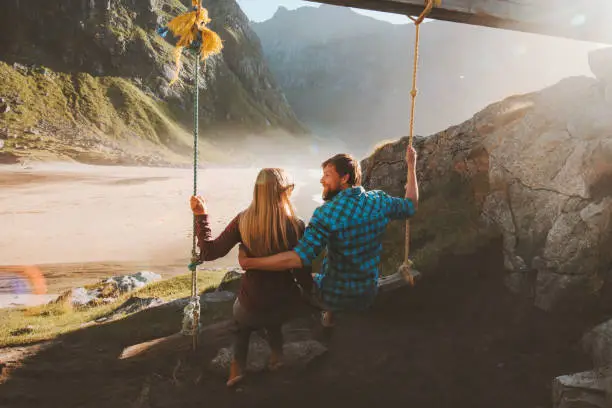 Photo of Couple in love on swing travel outdoor vacations lifestyle family relationship man and woman together enjoying Kvalvika beach and mountains view in Norway