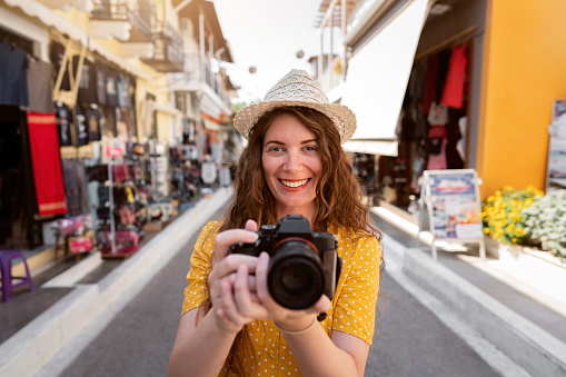 Portrait of a Caucasian woman traveler holding a camera, photographing streets of Vasiliki, on the island of Levkas, Greece.