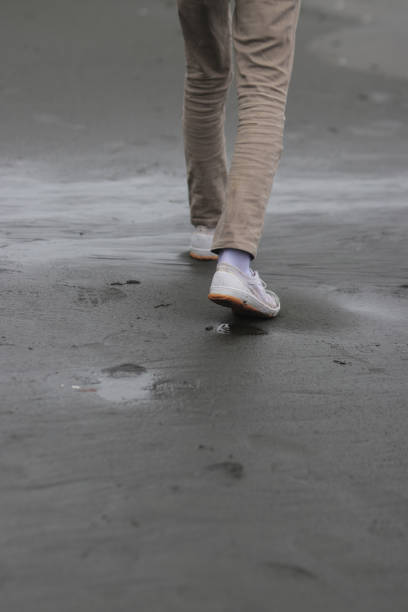 istock a lonely man walking on a black sand beach. Lonely concept background. 1330267759
