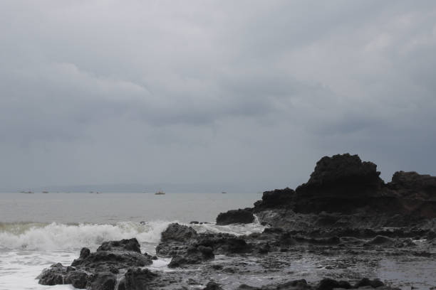 Big waves crashing rocks with dramatic grey cloudy sky on the Citepus beach Pelabuhan Ratu, Sukabumi, Indonesia.