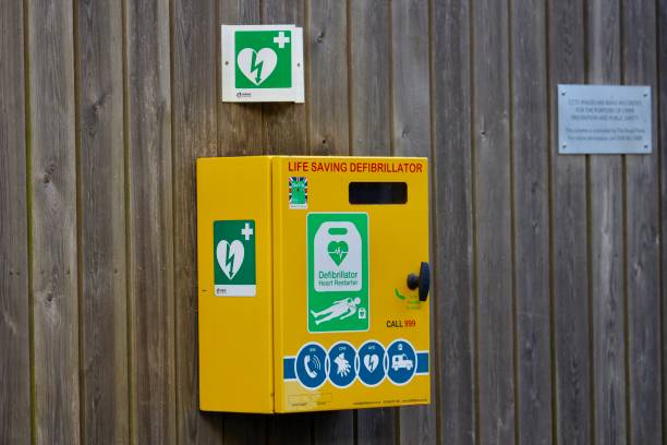 Defibrillator attached to the wooden wall in a park. London, UK- July 19, 2021: Defibrillator attached to the wooden wall in a park. An AED is a device that checks the heart's rhythm and sends a shock to the heart to restore a normal rhythm. defibrillator photos stock pictures, royalty-free photos & images