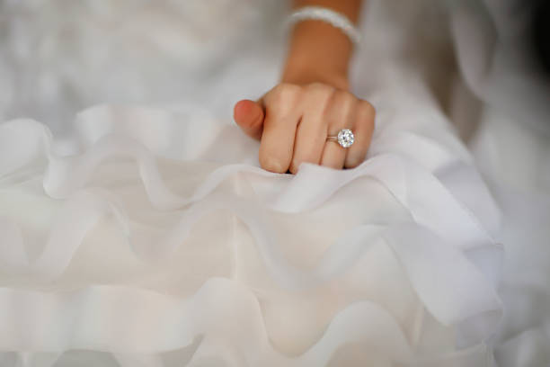 Bride's hand with beautiful diamond ring on white dress Bride's hand with beautiful diamond ring on white dress engagement ring stock pictures, royalty-free photos & images