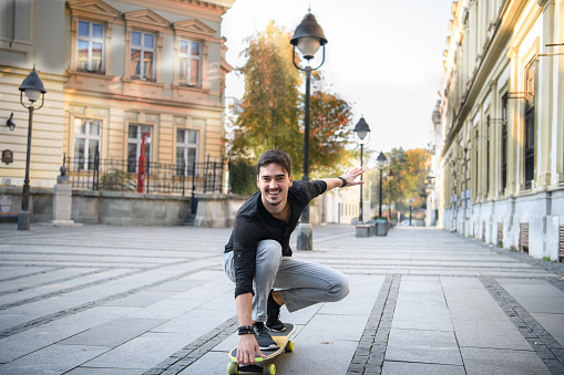 Happy Tourist on Vacation is Sightseeing the City. A Young Man is Having Fun in the City Streets and Riding a Skateboard.