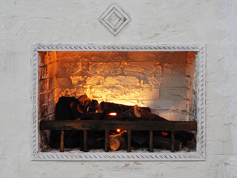 White decorative fireplace with wood and fake fire. Interior decor