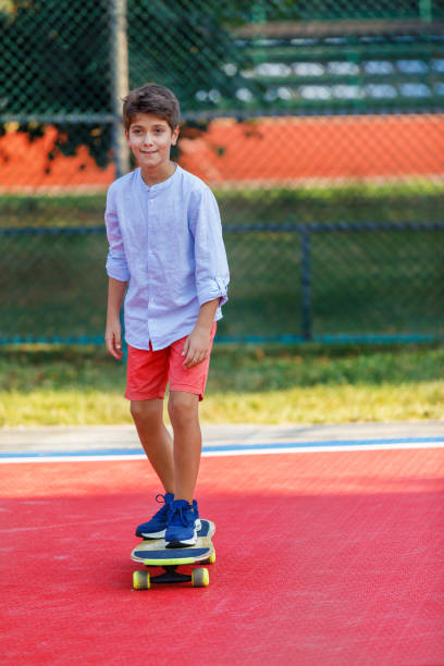 young boy sta cavalcando uno skateboard in un parco pubblico. - skateboard court foto e immagini stock