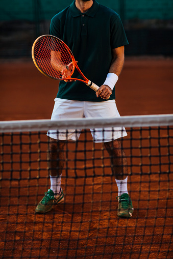 Unrecognisable fit tennis player standing on the net while playing a match