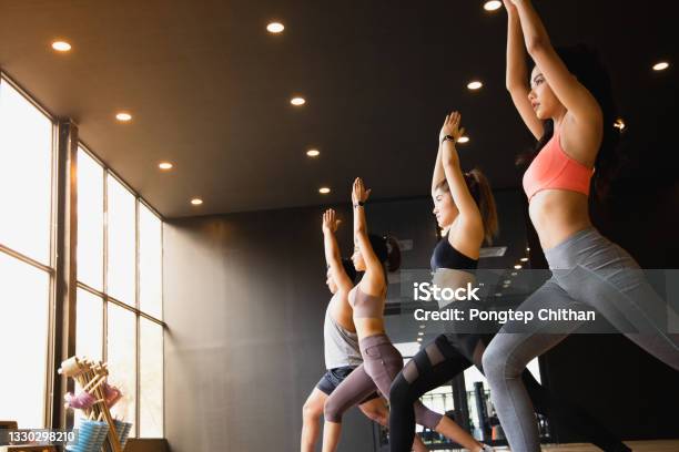 A Group Of Young Asian People Who Are In Good Shape Studying Yoga With A Trainer They Are In A Warrior 1 Pose Stock Photo - Download Image Now