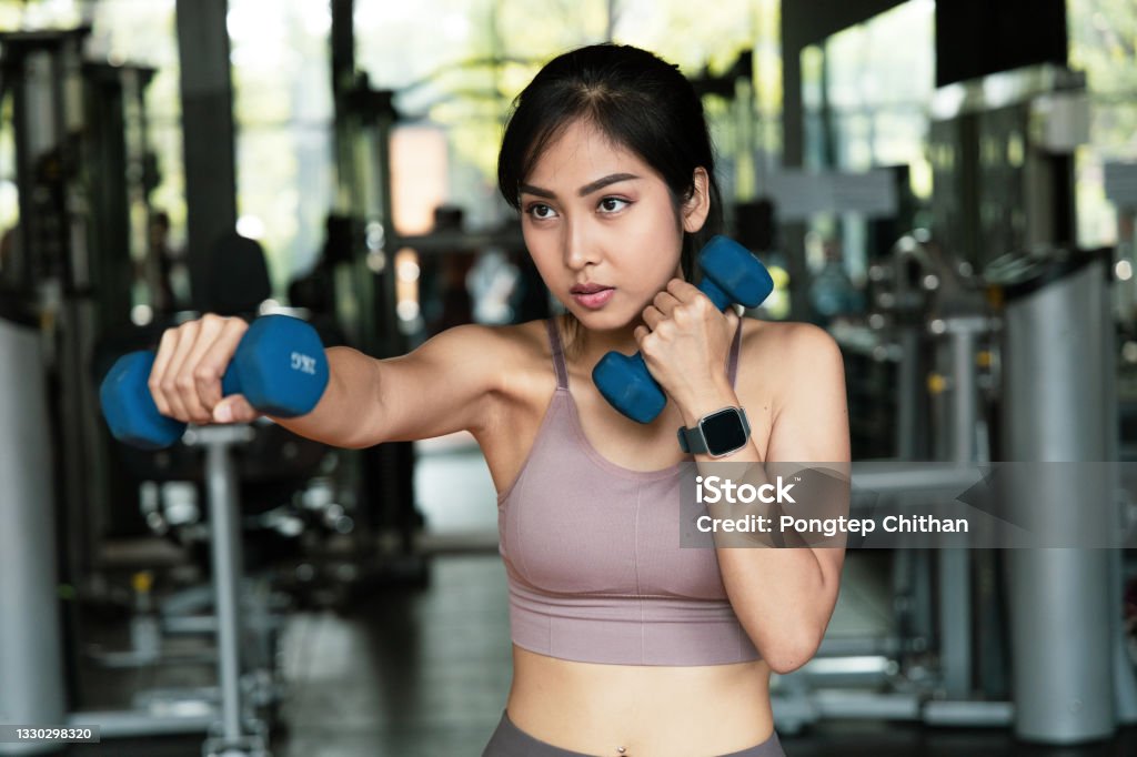 An Asian women Exercise with dumbbells for boxing in fitness gym.  With a boxing dumbbell workout boxers will develop the muscles in arms. self care and Lose weight concept High-intensity interval training Stock Photo