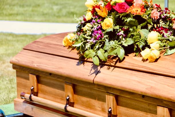 Floral arrangement on casket at graveside Beautiful floral arrangement on wooden casket at graveside service in cemetery coffin photos stock pictures, royalty-free photos & images