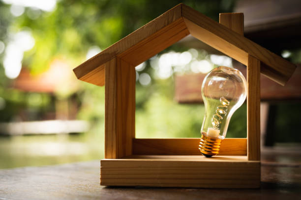 istock Light bulb with wood house on the table, a symbol for construction, Creative light bulb idea, power energy or business idea concept ecology, loan, mortgage, property or home. 1330300236
