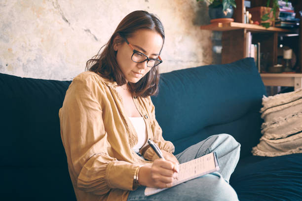 istock Shot  of a young woman making notes while relaxing on the sofa at home 1330309550
