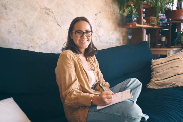 istock Shot  of a young woman making notes while relaxing on the sofa at home 1330309551