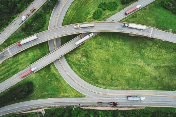 Aerial View of Semi Trucks Aerial view of semi trucks on a highway interchange. (Composite image) drone point of view road stock pictures, royalty-free photos & images