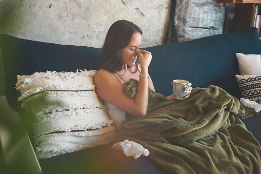 Foto de una mujer joven que sufre de dolor de cabeza y se siente enferma en el sofá de casa photo