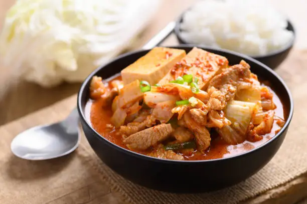 Kimchi soup with tofu and pork in a bowl eating with cooked rice, Korean food