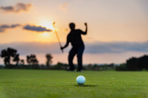 silhouette golfeur montrant le bonheur lors de la victoire dans le jeu, balle de golf blanche sur l’herbe verte du terrain de golf avec fond flou. - golf golf swing men professional sport photos et images de collection