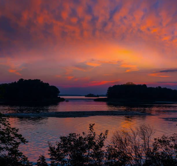 istock dramatic sunset over quiet lake, tree on lake coast silhouette at the twilight 1330314729