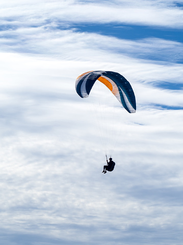 Vertical landscape photo of a man paragliding on a sunny day above the coastline at Lennox Head, near Byron Bay, NSW