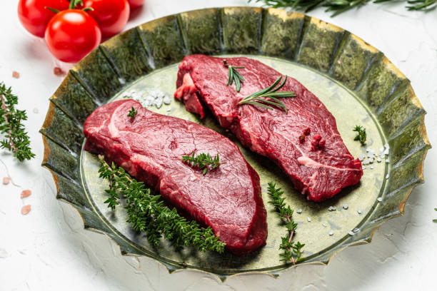 Raw beef tenderloin lies on a cutting board and spices for cooking on a  black table, top view - a Royalty Free Stock Photo from Photocase