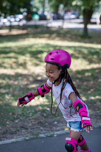 Cute black girl having fun on roller skates in the park.