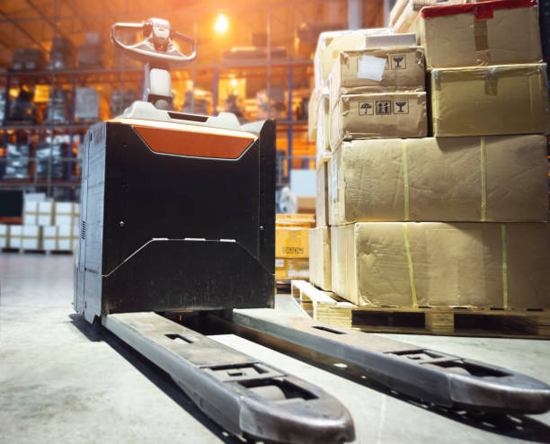 istock Electric Forklift Pallet Jack with Package Boxes on Pallet at The Storage Warehouse. Shipping Warehouse Logistics. 1330326123