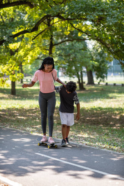 fofo garoto de 10 anos aprendendo sua mãe andando de skate - 25 30 years adult african descent bonding - fotografias e filmes do acervo