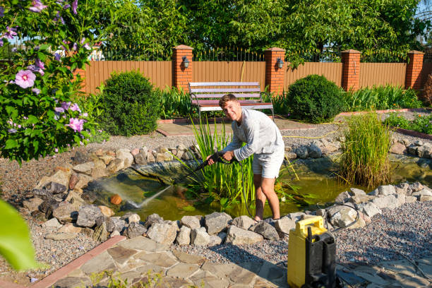 istock man cleans garden pond bottom with high-pressure washer from mud and sludge. 1330331940