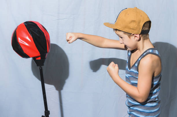 boy in brown cap and suspenders trains with punching ball - 5943 imagens e fotografias de stock