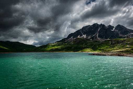 Lake in the Italian Alps with storm clouds in the sky and rays of Sun on the water