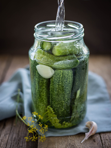 Pouring brine into a pickling jar .  Pickles  .  Cucumbers in a glass jar.