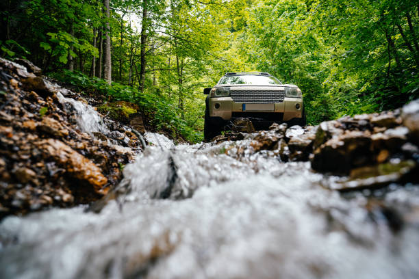 숲 속의 바위 사이로 흐르는 시냇물 옆의 suv 자동차 - mud terrain 뉴스 사진 이미지