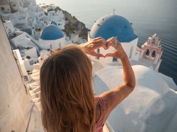 istock Woman contemplates Santorini from top, makes heart with hands 1330351966